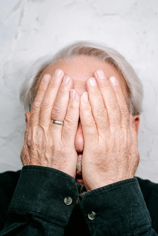 the older man is covering his eyes with his hands