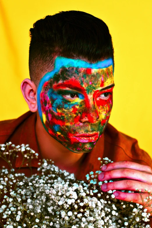 a man wearing colorful face paint poses for the camera