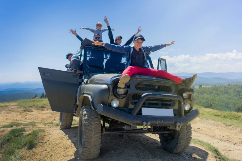 four people on a jeep with their arms raised