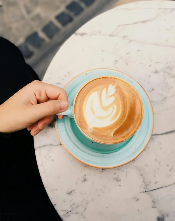 someone holding a spoon over a cup of latte art