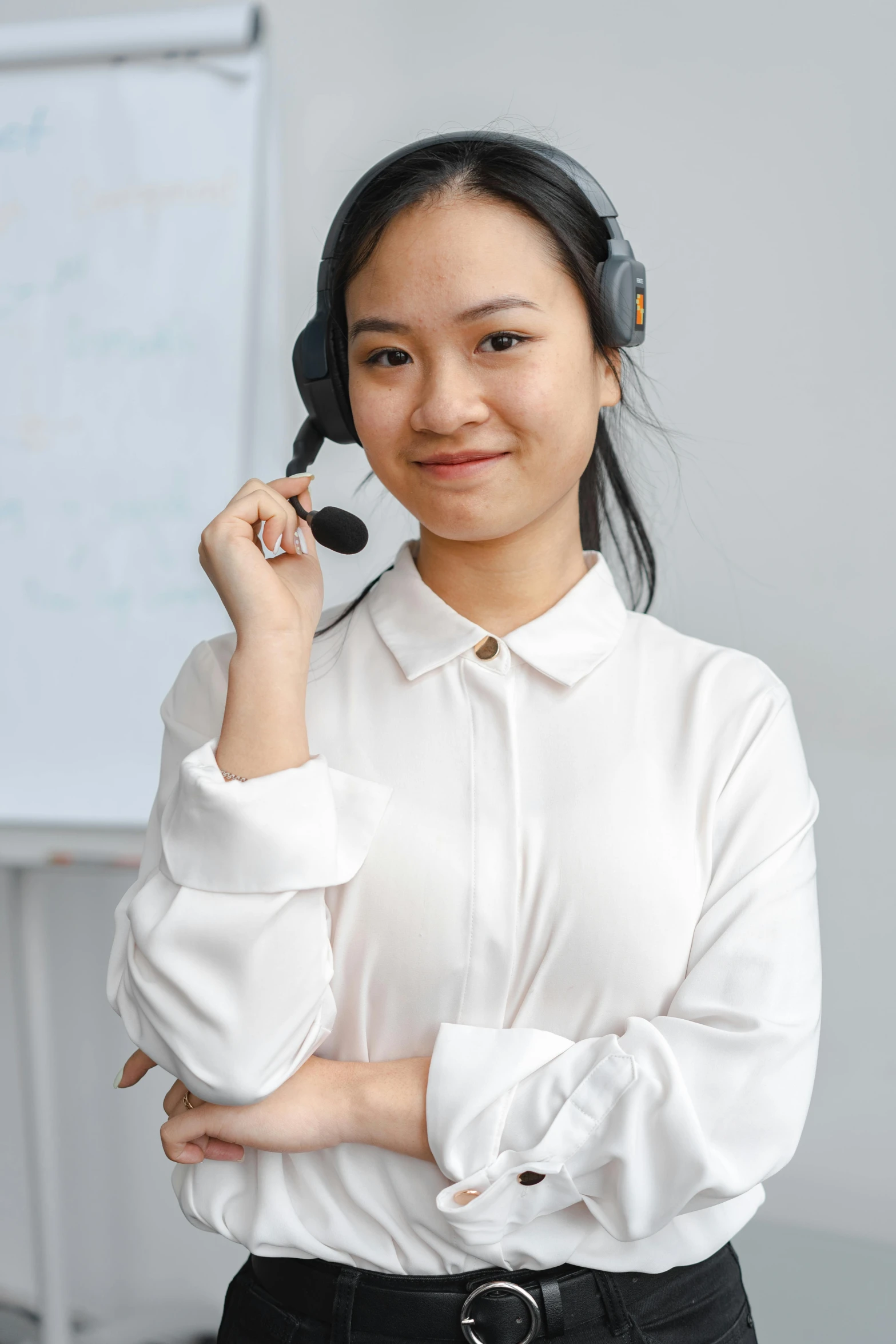 an asian woman wearing a white shirt and holding a headset