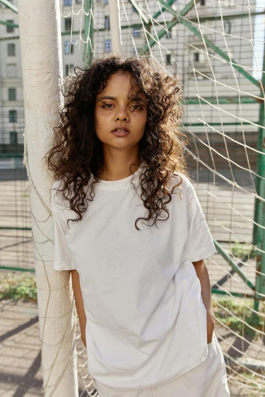 a woman stands near the soccer goal in a white outfit