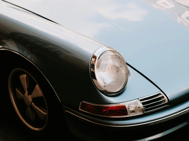 the front of a blue classic car parked on a road