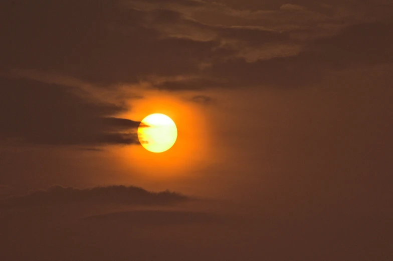 the sun is surrounded by clouds and fog