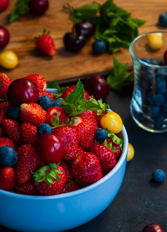 a blue bowl filled with berries and cherries