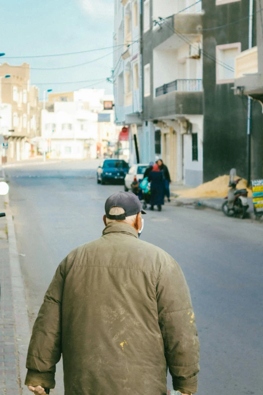 a person walking down a street with a pair of skis in his hand