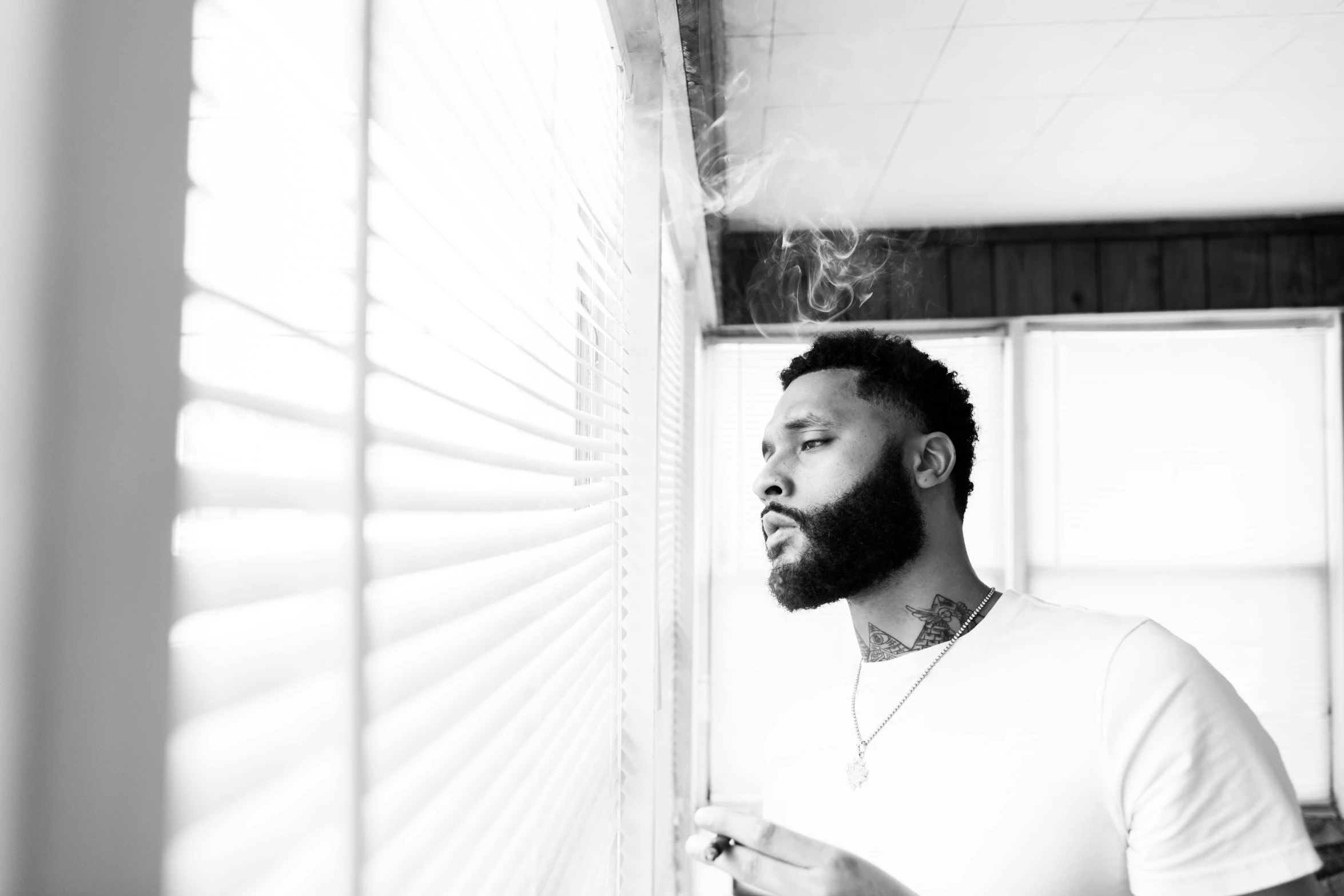 man in white shirt smoking cigarette in a sunny room