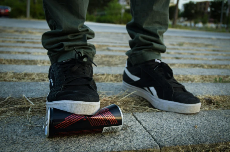 the person's feet stand on a black and white sneaker