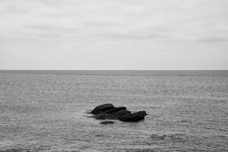 a man walking down the ocean towards some rocks