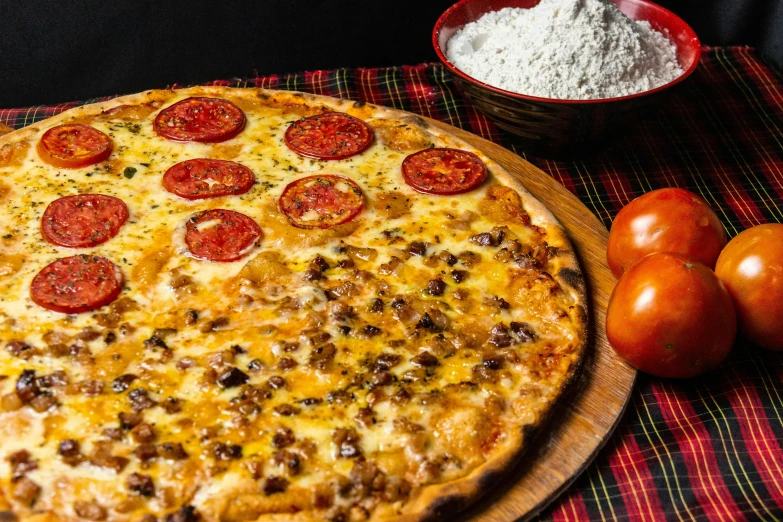 a pizza on a  board with peppers and tomatoes next to it