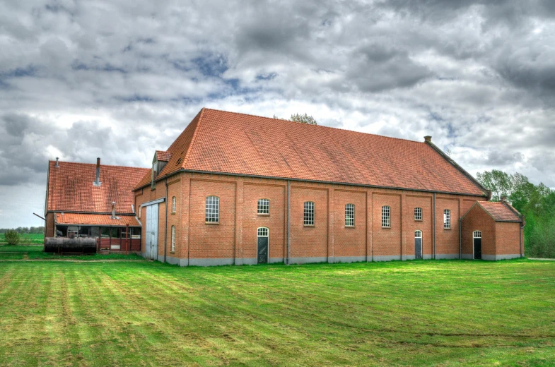 a brick building with a sky background and a grassy field behind it