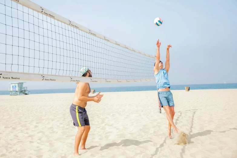 two men are playing volleyball on the beach