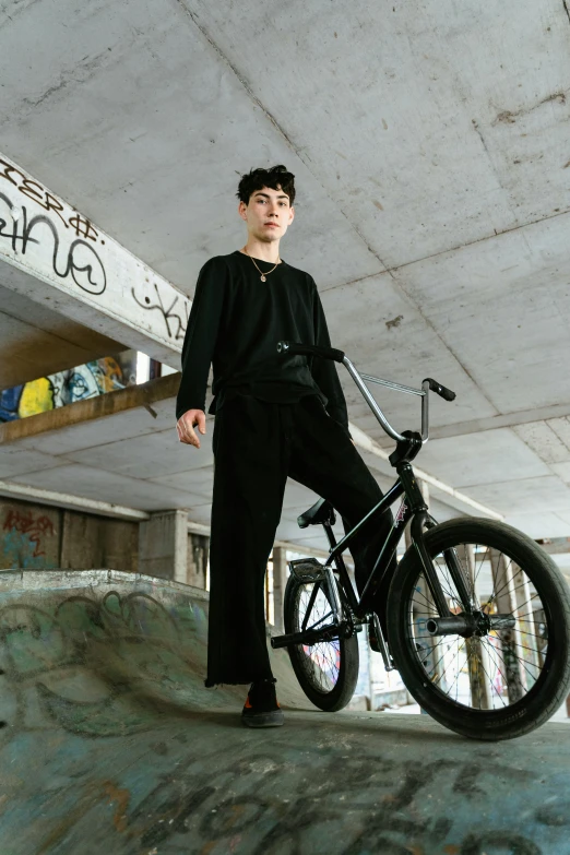 a young man is posing with his bike in a parking garage