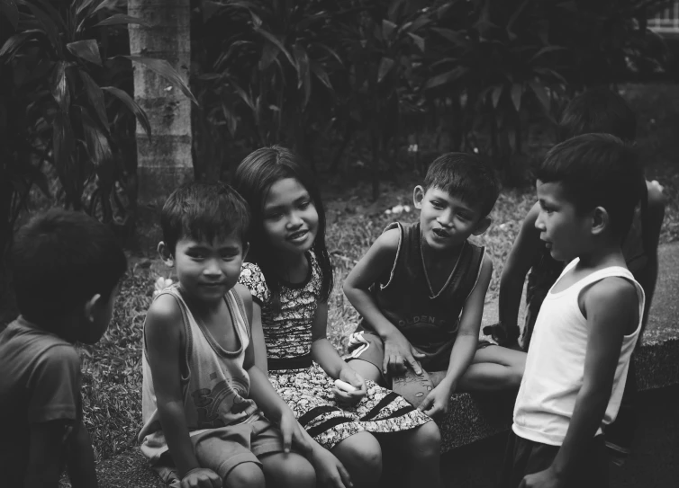 group of children sitting on a wall in a garden