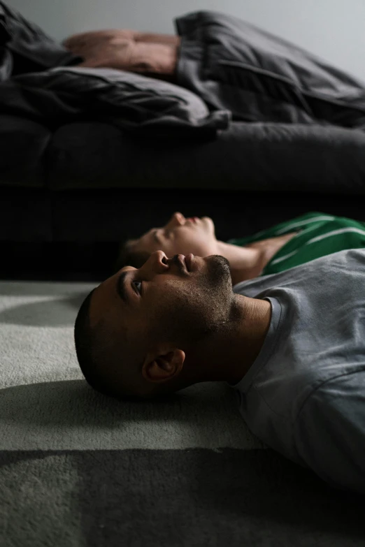 a man lying on the ground near a bed