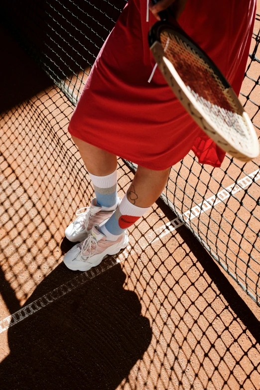 a person holding a tennis racket is standing on a court