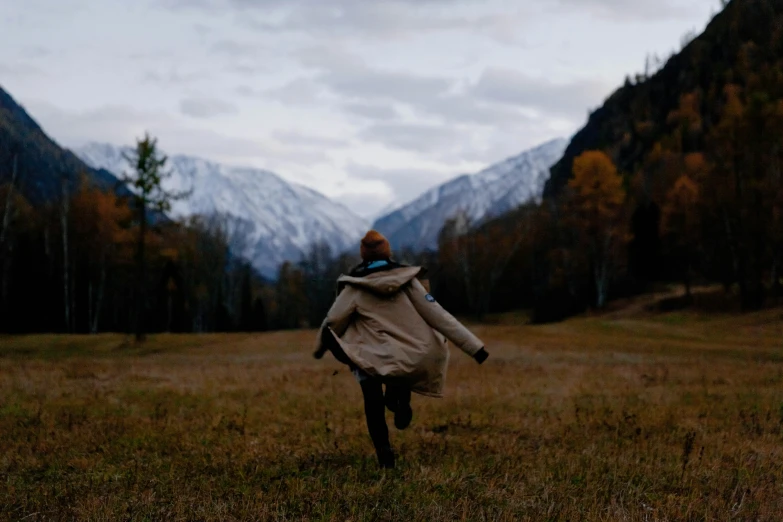 a person running in an open field with mountains behind them