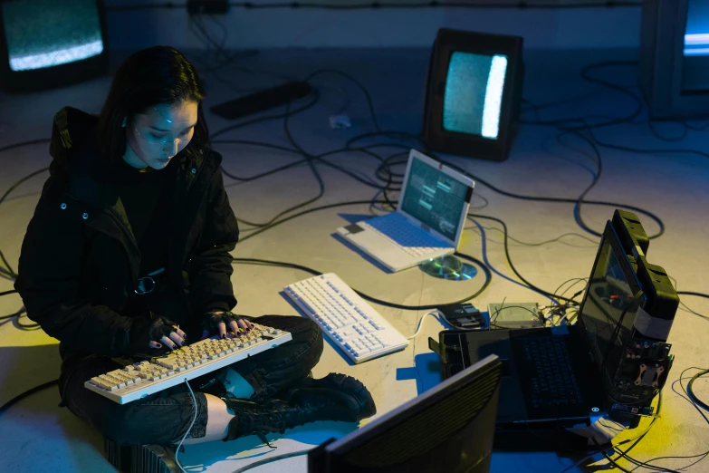 woman sitting in front of a computer monitor surrounded by electronic devices