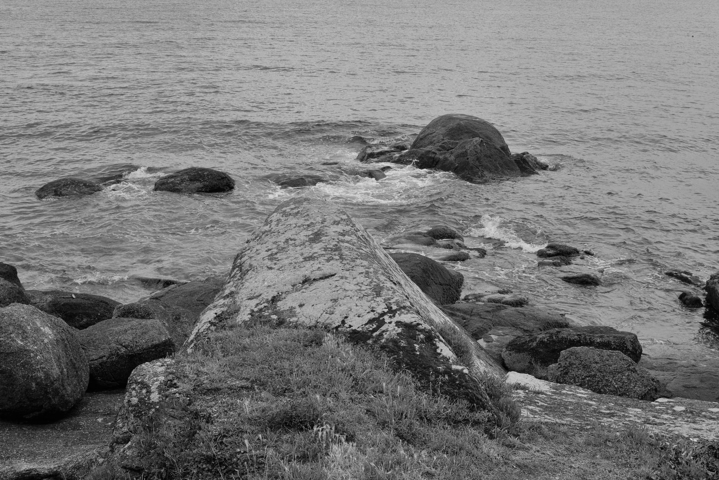 a man standing on a large rock out in the ocean