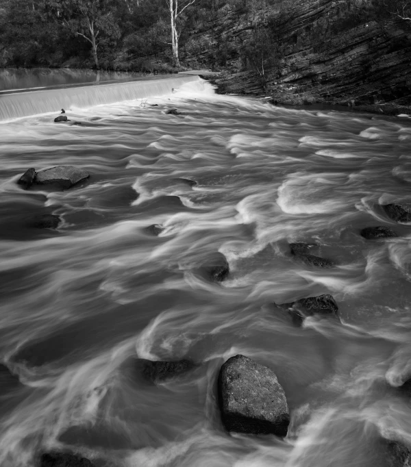 a river runs down rocks with a boat sailing on it