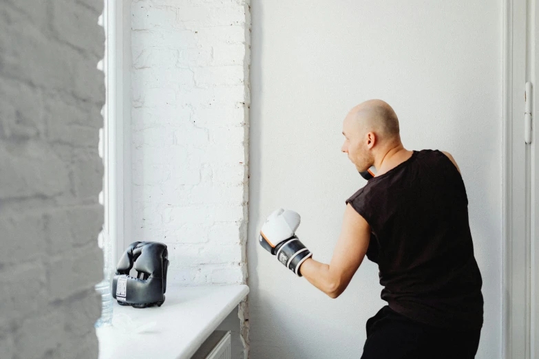 a man with boxing gloves on leaning against a wall