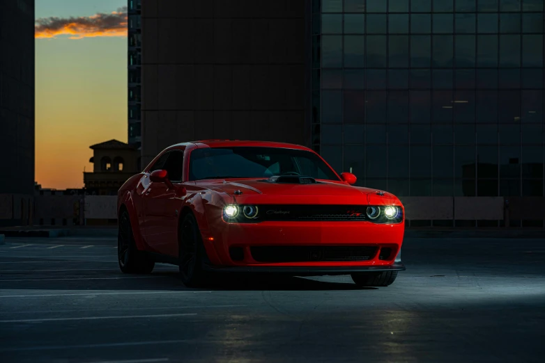 red dodge demon car parked on concrete in front of tall building