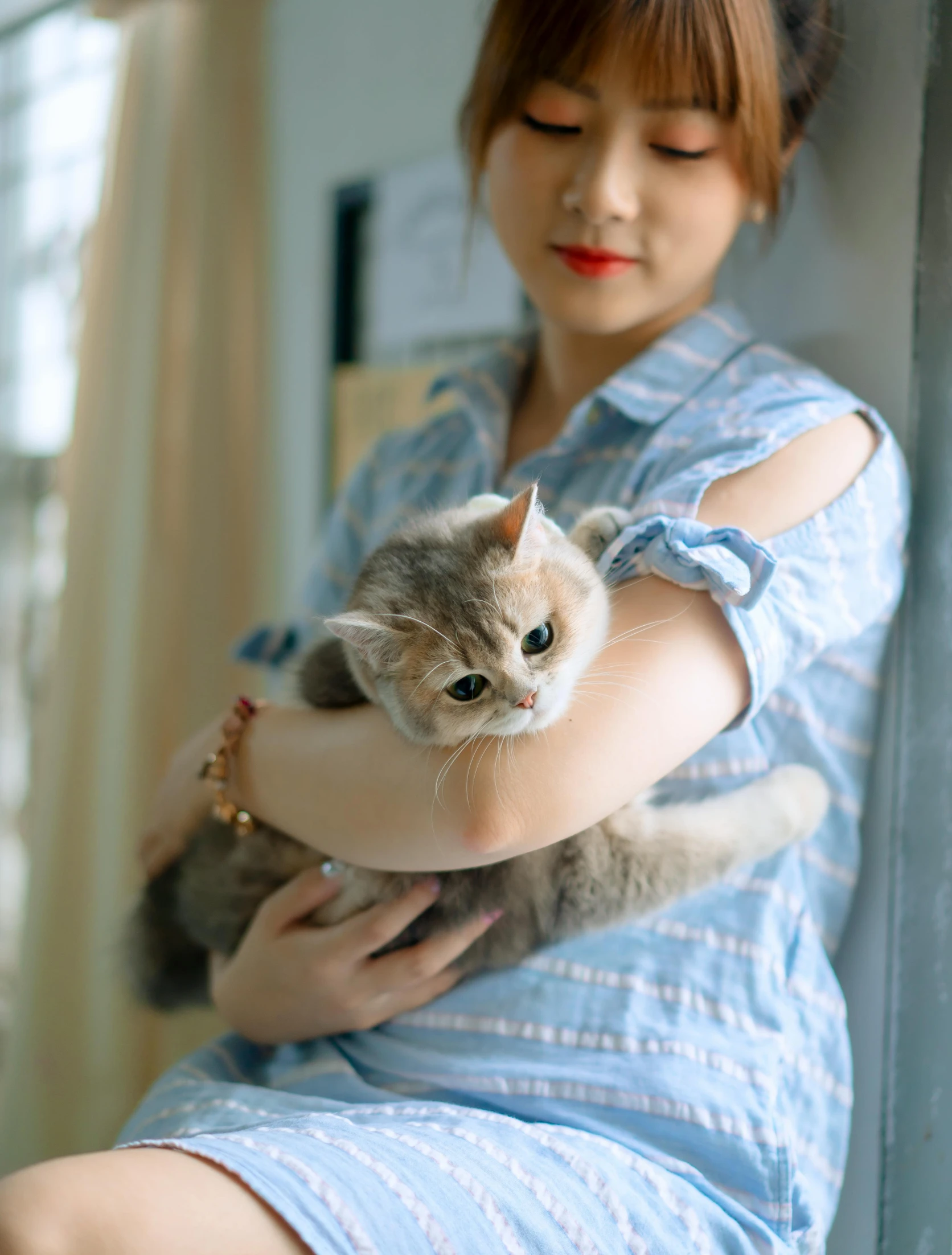 a young woman is holding a cat and staring at the camera