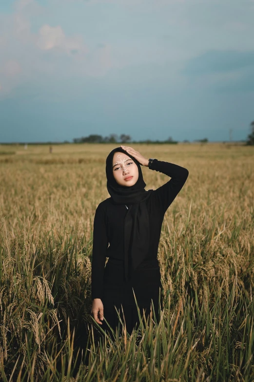 a woman standing in the middle of a field holding her head in her hair