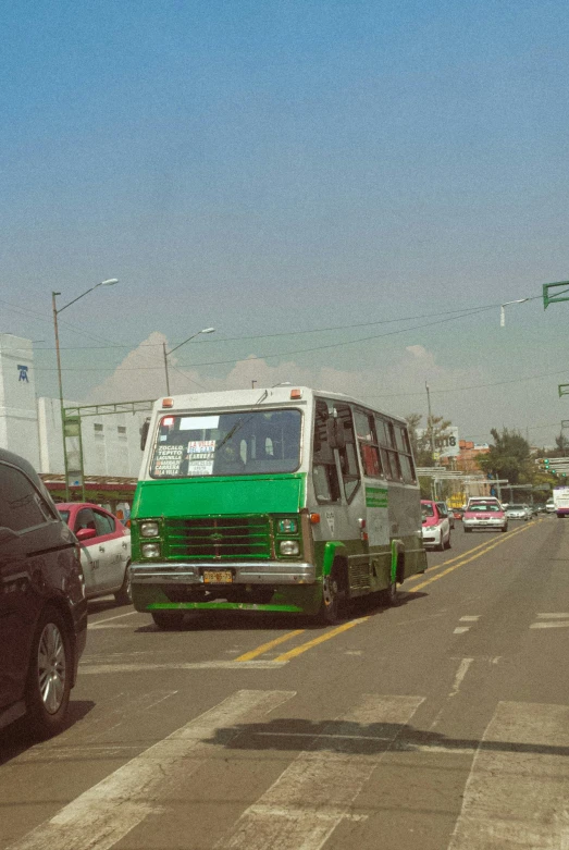 some cars are on the road and a green truck is driving down the road