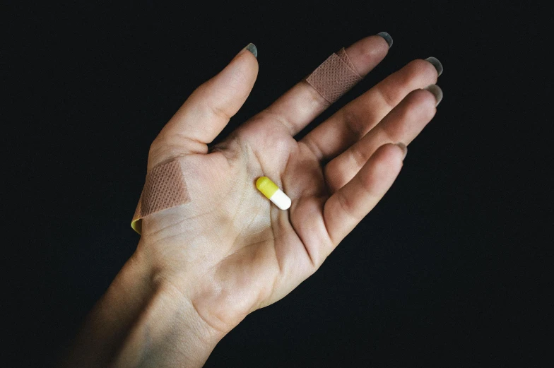 a person holding their hand with two pills in it