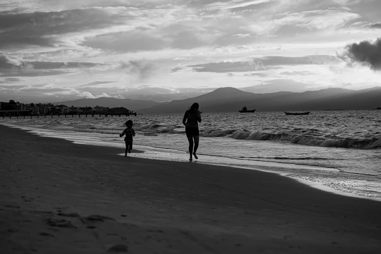 two people walking on a beach near the ocean