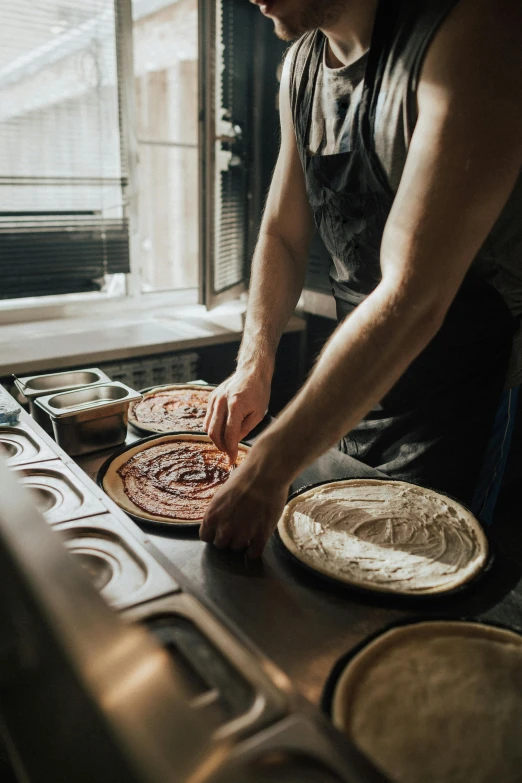 a man standing over an oven preparing pizza