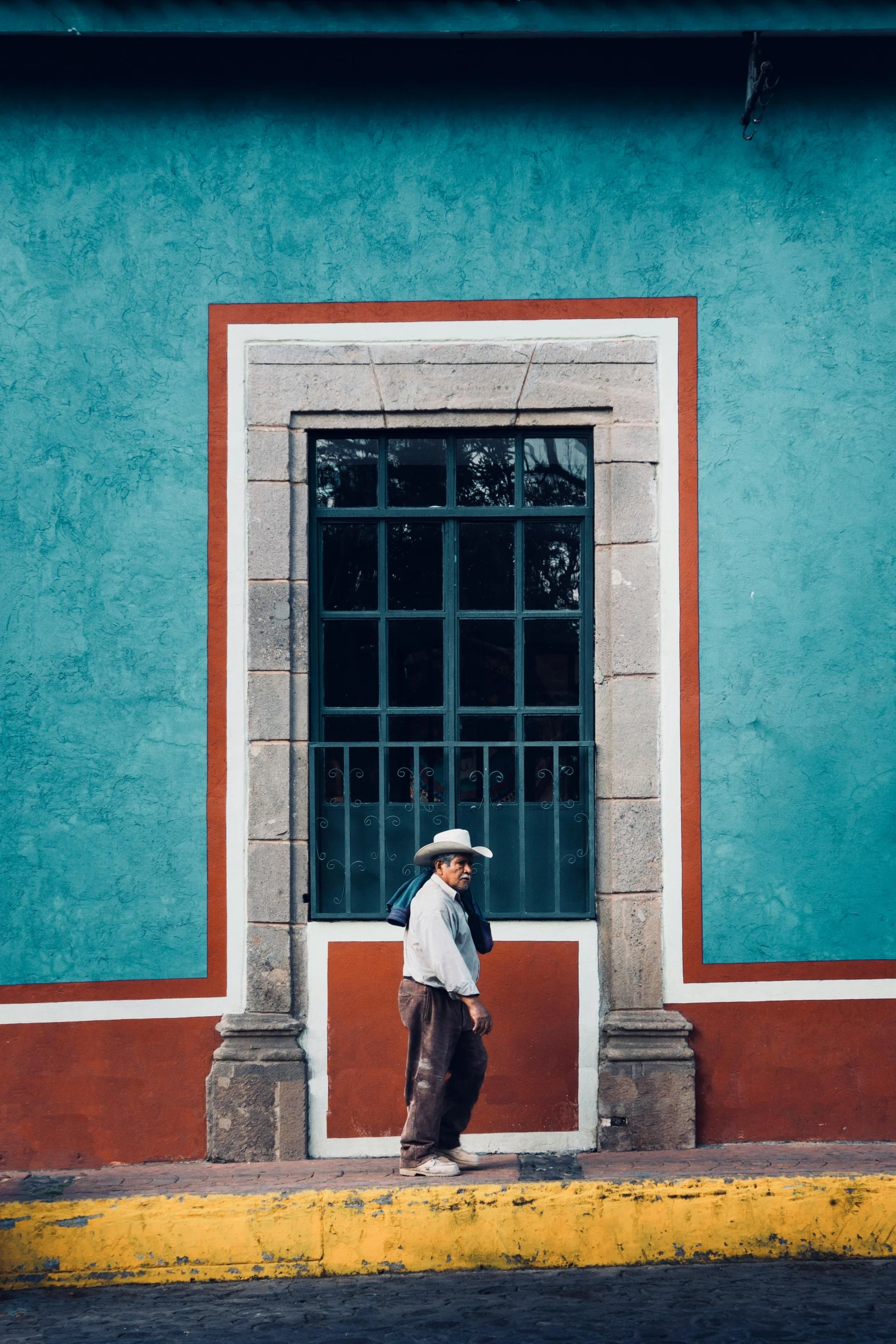 a man in a cowboy hat walking past a building