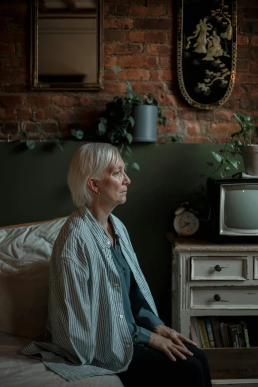 an older woman sitting on the bed looking at soing