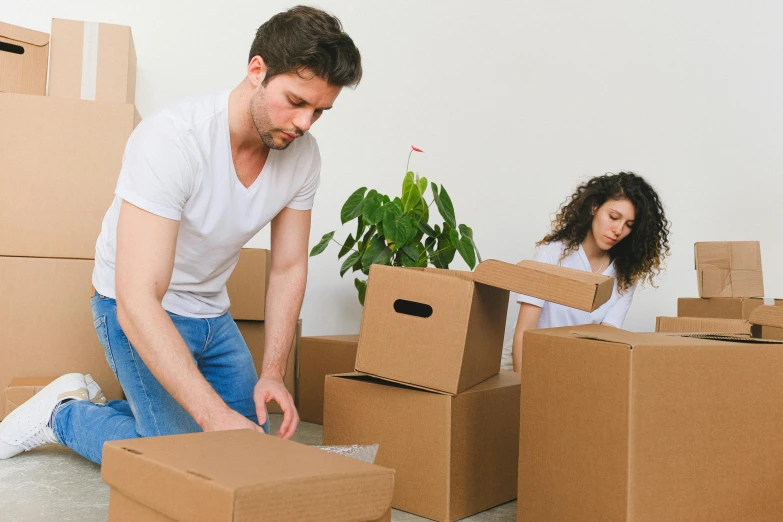 a man and a woman sitting on the floor surrounded by boxes