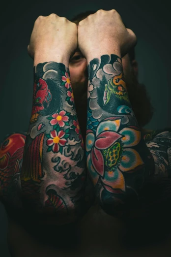 man's arm covered with tattooed arm sleeves and flowers