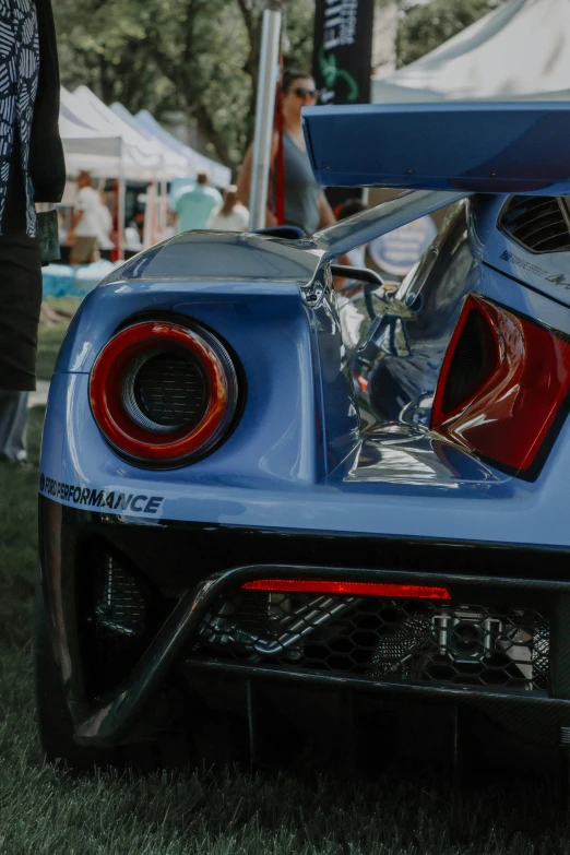 the rear end of a blue car with chrome parts