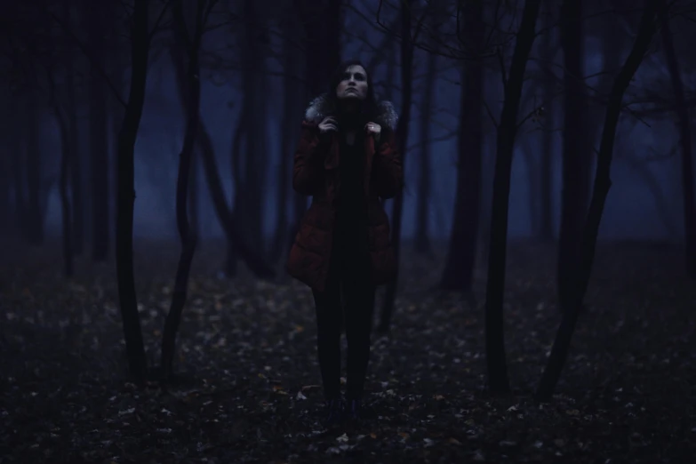 a woman standing in the woods with her arms around her neck