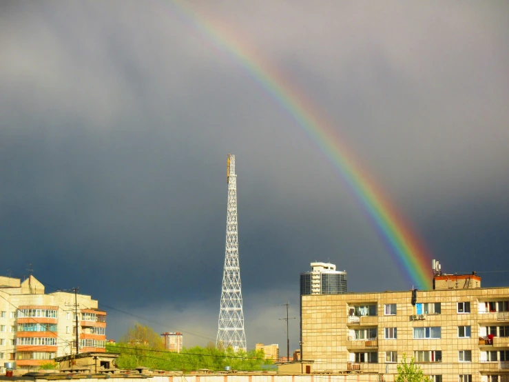 the rainbow is visible in the dark cloudy sky above a city