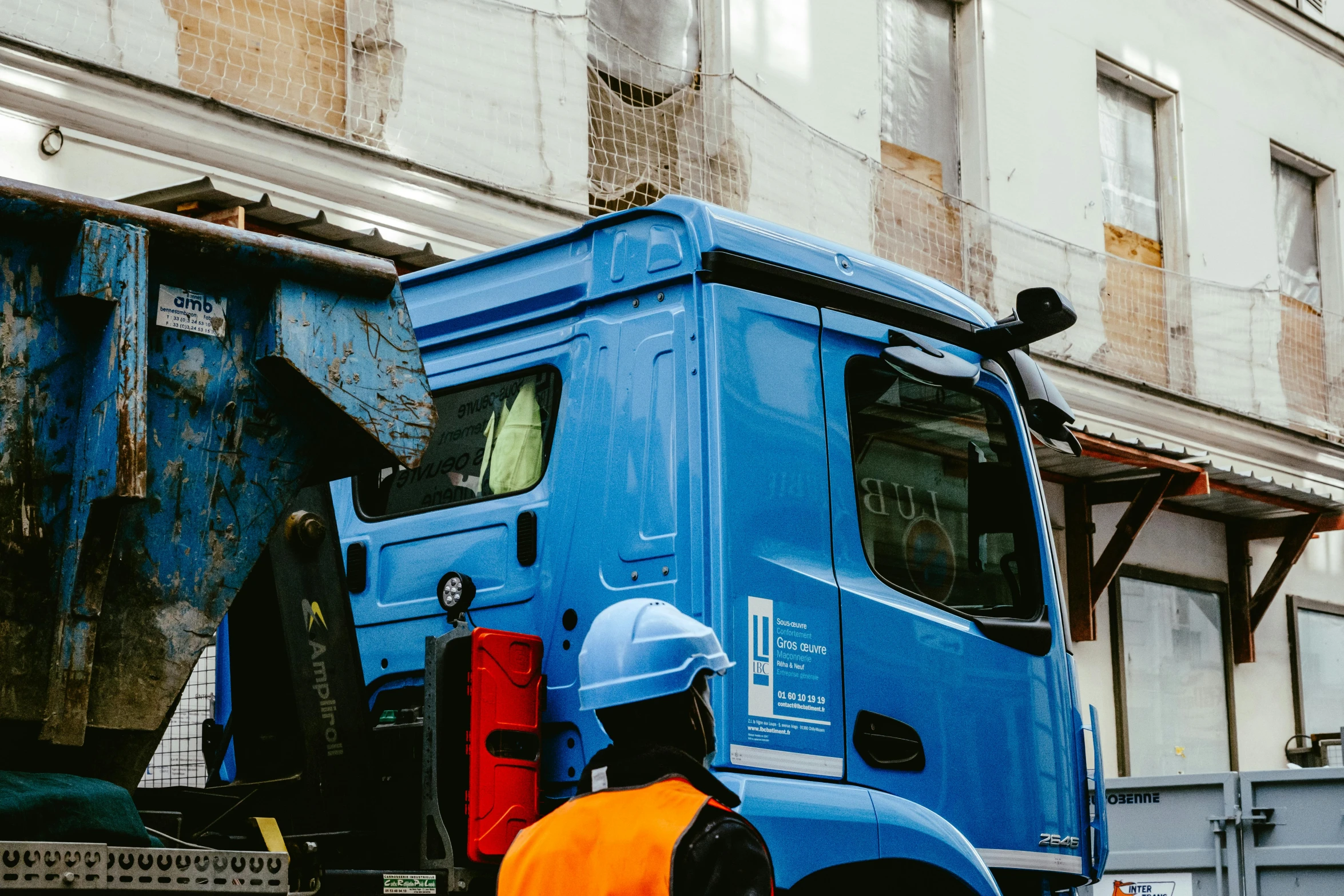 blue garbage truck and worker on city street