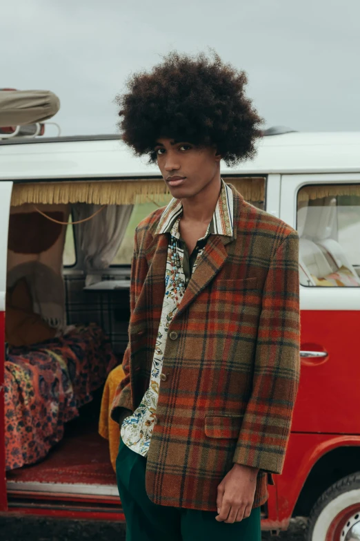 a young man stands in front of a red van