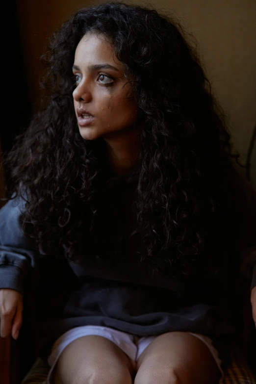 woman with curly black hair sitting in chair