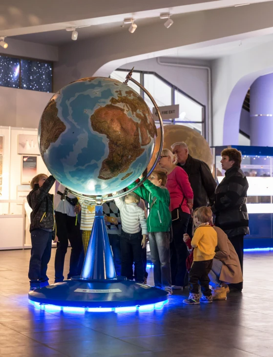 people are standing around a blue and white globe