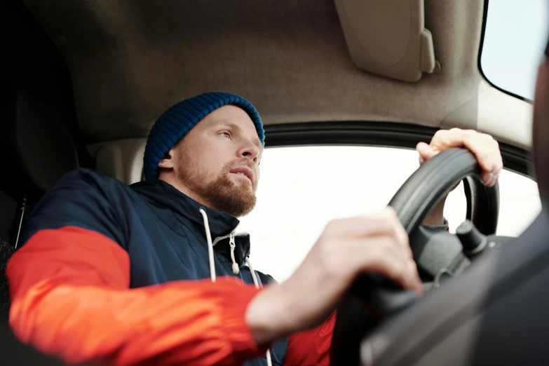 a man driving his car looking up at the steering wheel