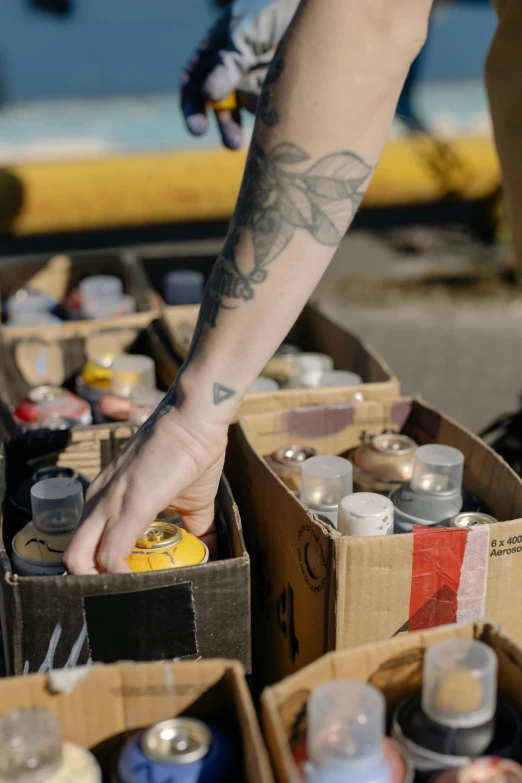 someone is reaching for cans from boxes that are filled with soda