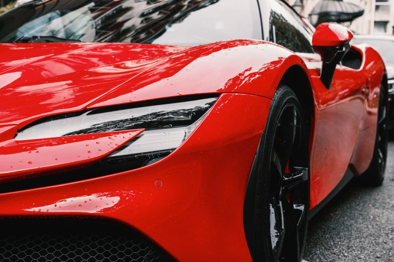 the front end of a red sports car parked in the street