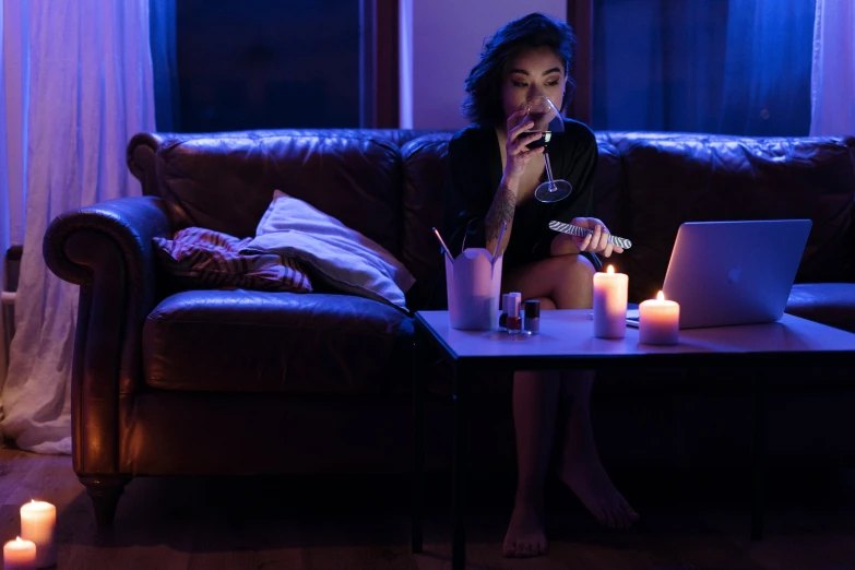 a woman sits on a sofa looking at a laptop