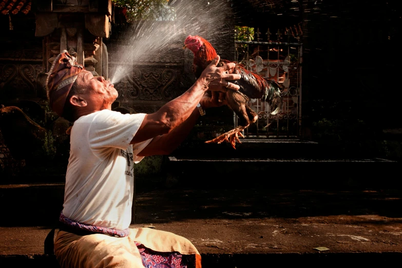 a man spraying water at chickens with his hands