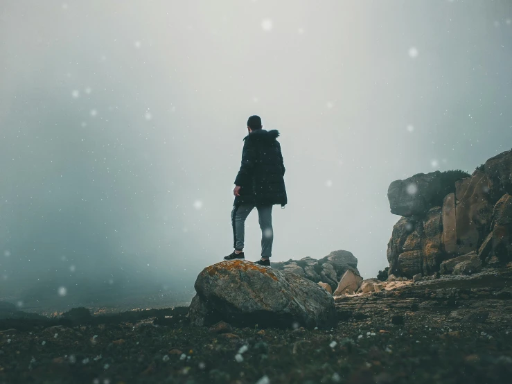 a person in a parka is standing on rocks