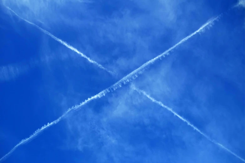 two airplanes fly in the blue sky leaving contrails